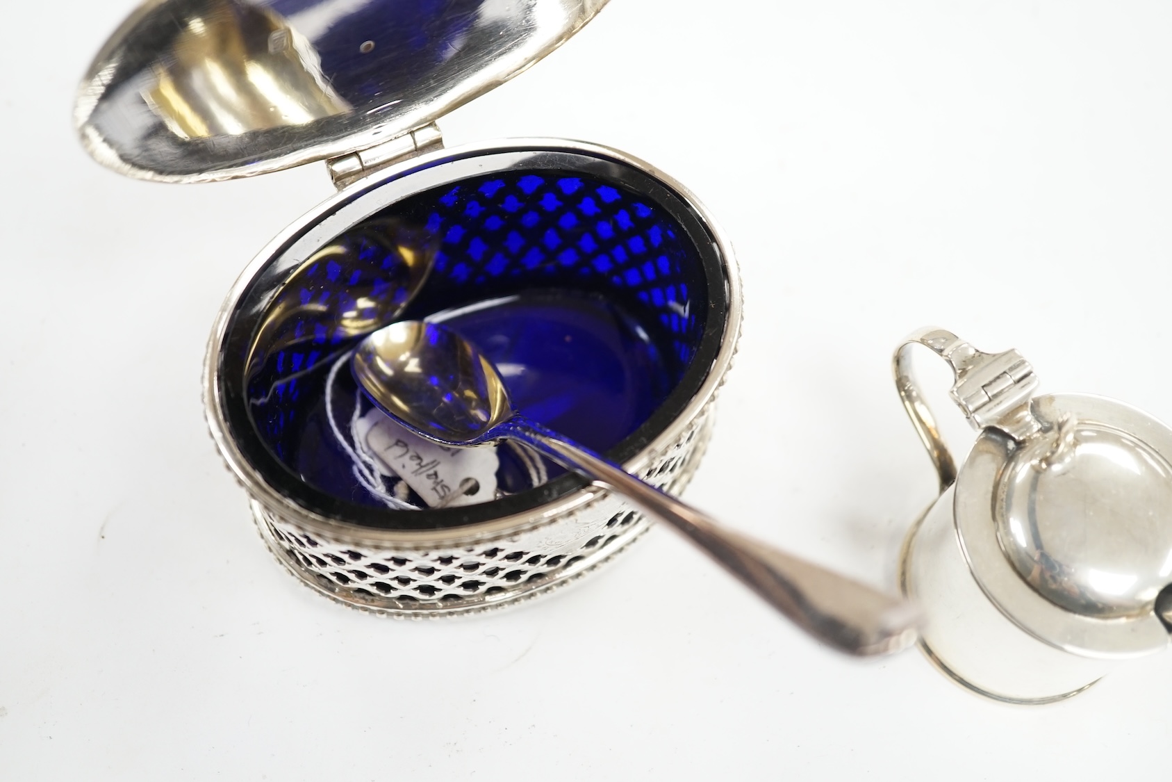 A Victorian pierced silver oval mustard pot by Henry Wilkinson & Co Ltd, Sheffield, 1851, 84mm, with blue glass liner and associated plated spoon, together with a smaller later silver mustard pot. Condition - fair